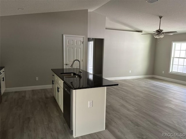 kitchen featuring a sink, wood finished floors, white cabinetry, dishwashing machine, and lofted ceiling