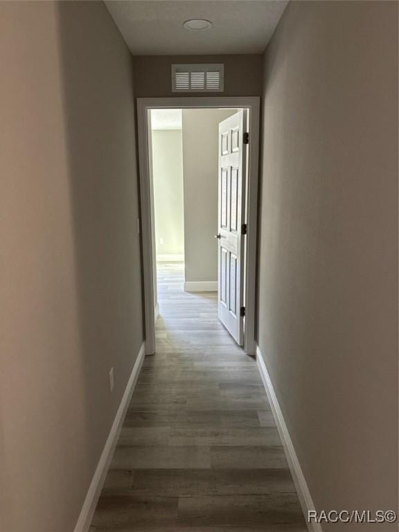 corridor with visible vents, baseboards, and wood finished floors