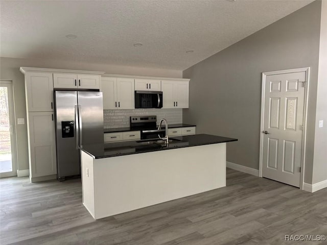 kitchen featuring a sink, dark countertops, appliances with stainless steel finishes, and white cabinetry