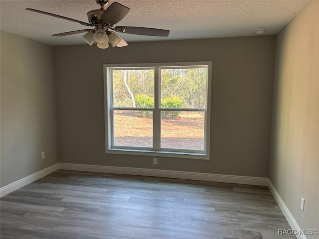 unfurnished room featuring baseboards, a textured ceiling, and wood finished floors