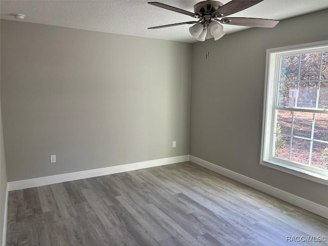 spare room featuring ceiling fan, a textured ceiling, baseboards, and wood finished floors