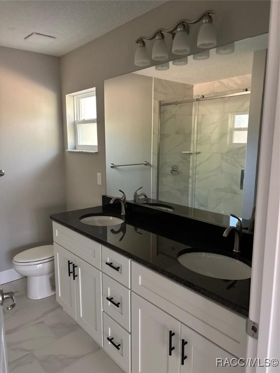 full bathroom featuring marble finish floor, toilet, and a sink