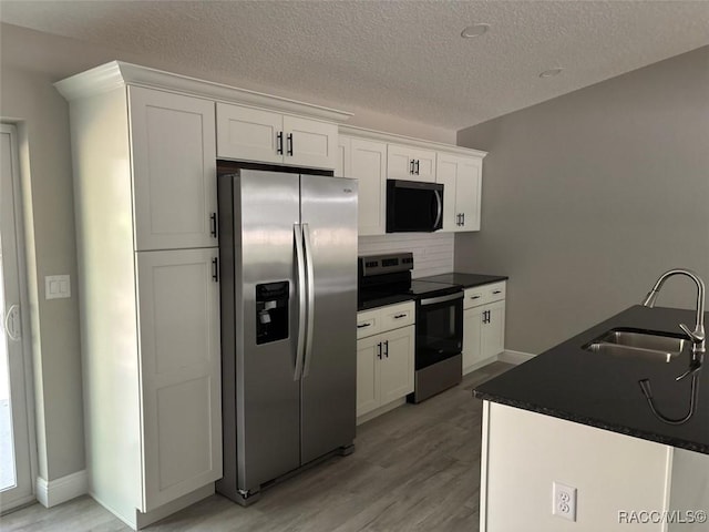 kitchen featuring a sink, stainless steel appliances, dark countertops, and white cabinetry