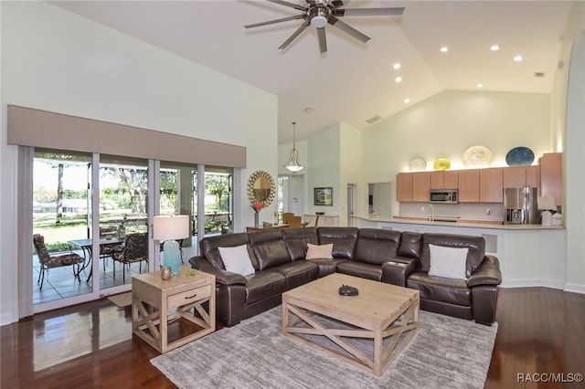 living room featuring dark wood-type flooring, high vaulted ceiling, and ceiling fan