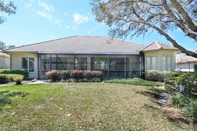 back of property with a yard and glass enclosure