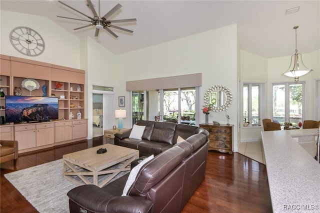 living room featuring built in shelves, ceiling fan, dark hardwood / wood-style flooring, and vaulted ceiling