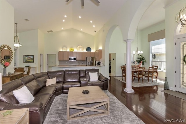 living room featuring dark hardwood / wood-style floors, high vaulted ceiling, and decorative columns