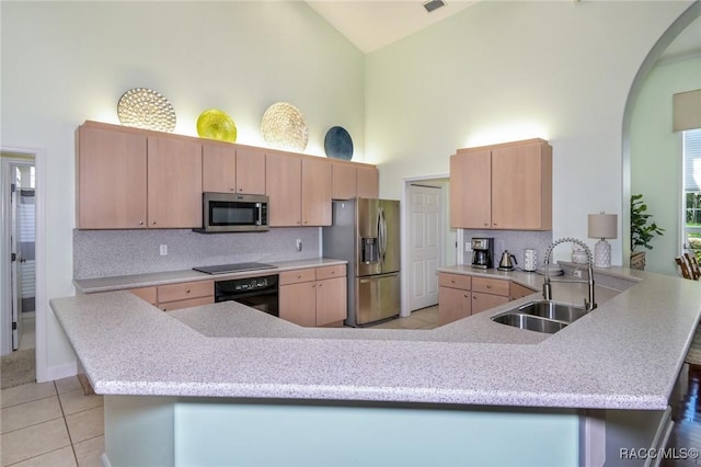 kitchen featuring sink, high vaulted ceiling, light brown cabinets, kitchen peninsula, and black appliances