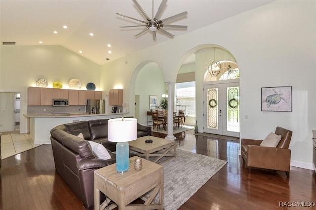 living room with french doors, high vaulted ceiling, decorative columns, and light wood-type flooring