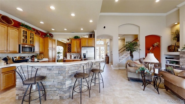 kitchen with appliances with stainless steel finishes, light countertops, glass insert cabinets, and a kitchen breakfast bar