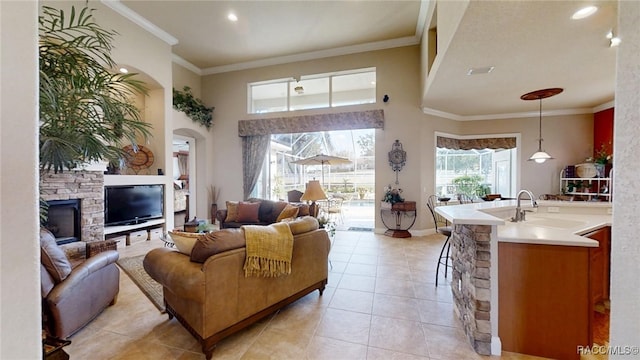 living area with visible vents, a high ceiling, ornamental molding, and light tile patterned flooring