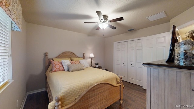 bedroom featuring visible vents, baseboards, a ceiling fan, dark wood-style floors, and a closet