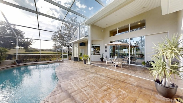 outdoor pool featuring glass enclosure and a patio