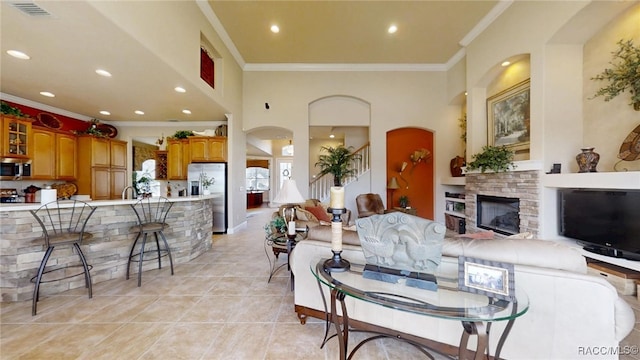 living area with ornamental molding, stairway, light tile patterned flooring, and a fireplace