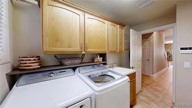 washroom featuring visible vents, light tile patterned flooring, washing machine and dryer, and cabinet space