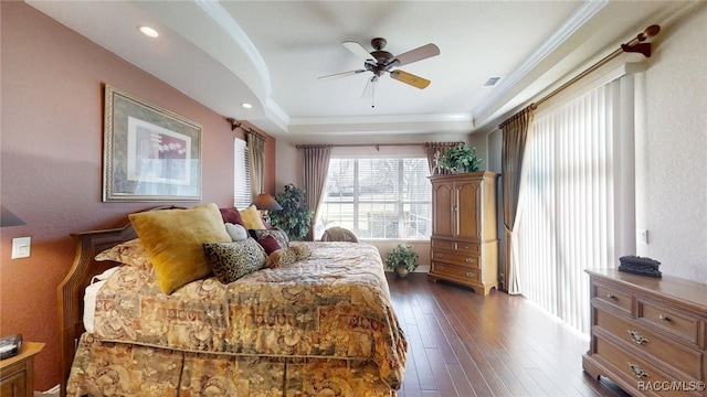 bedroom with visible vents, dark wood-style floors, a tray ceiling, crown molding, and recessed lighting