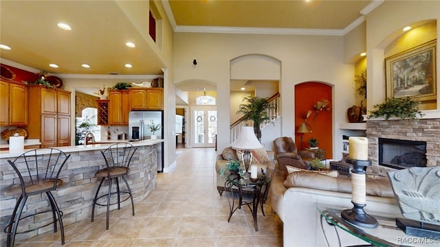 living area featuring french doors, a fireplace, light tile patterned floors, recessed lighting, and ornamental molding