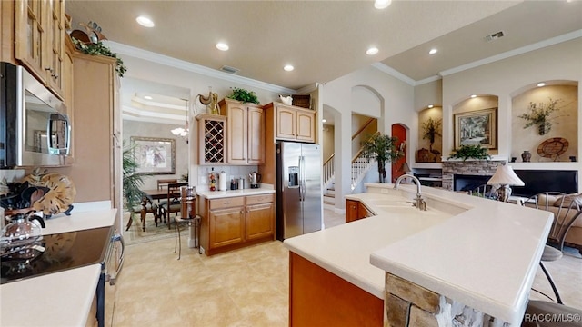 kitchen featuring light countertops, visible vents, appliances with stainless steel finishes, a sink, and a stone fireplace