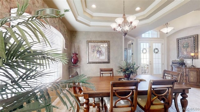 dining room with a notable chandelier, french doors, a raised ceiling, and crown molding