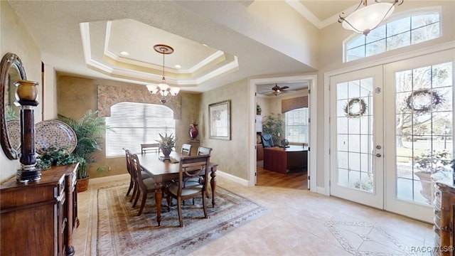 dining area with a healthy amount of sunlight, a tray ceiling, crown molding, and french doors