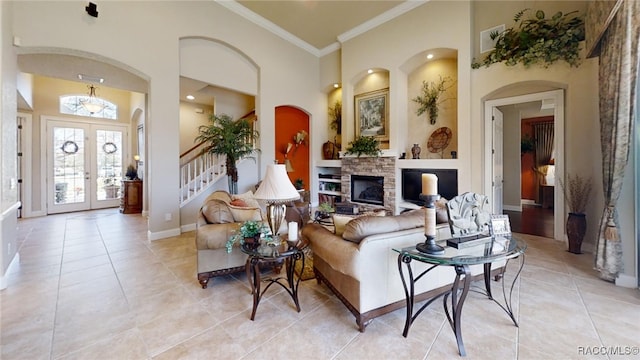 living room with light tile patterned floors, a stone fireplace, a towering ceiling, french doors, and crown molding