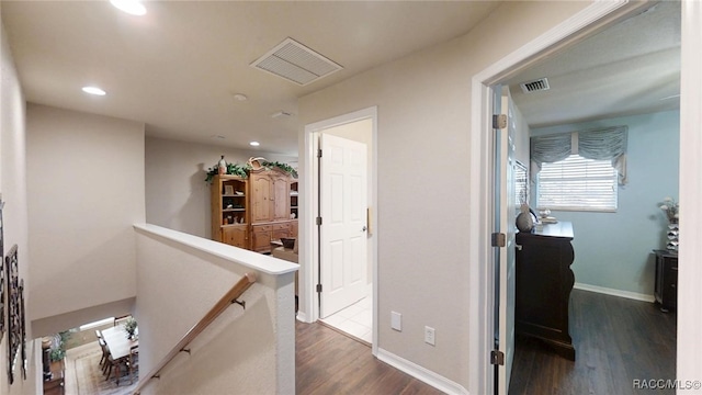 corridor featuring visible vents, baseboards, dark wood-style flooring, an upstairs landing, and recessed lighting