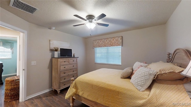 bedroom featuring dark wood-style flooring, visible vents, a textured ceiling, and baseboards