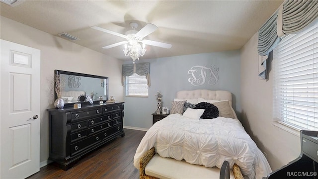 bedroom featuring a ceiling fan, dark wood-style flooring, visible vents, and baseboards