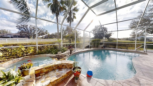 outdoor pool with glass enclosure, a patio, and an in ground hot tub