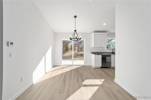 dining room with a wealth of natural light, a notable chandelier, light wood-style flooring, and baseboards