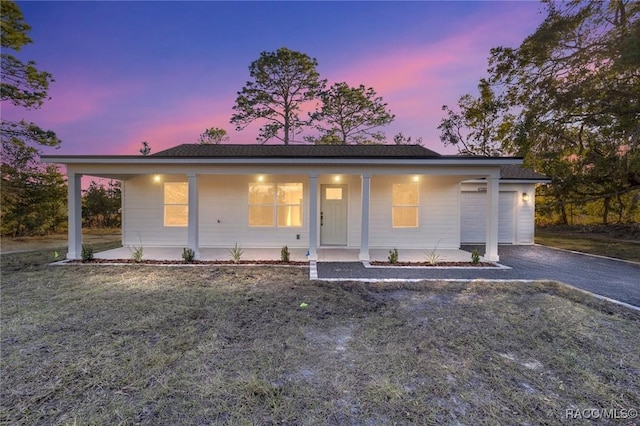 view of front of property featuring a porch, a yard, and a garage