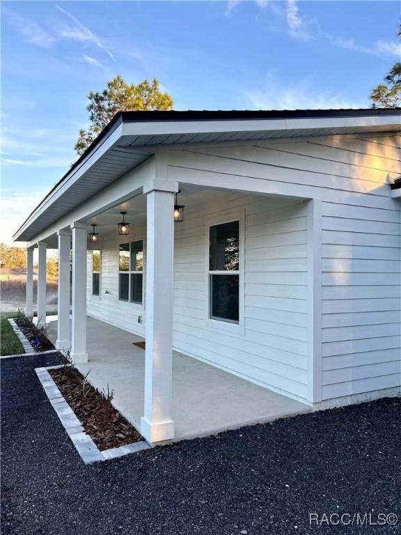 view of side of home featuring covered porch and a patio area