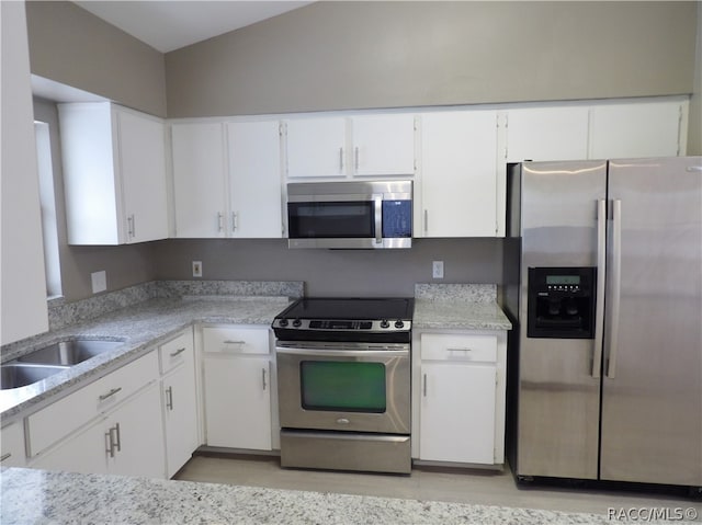 kitchen with white cabinets, lofted ceiling, sink, and appliances with stainless steel finishes