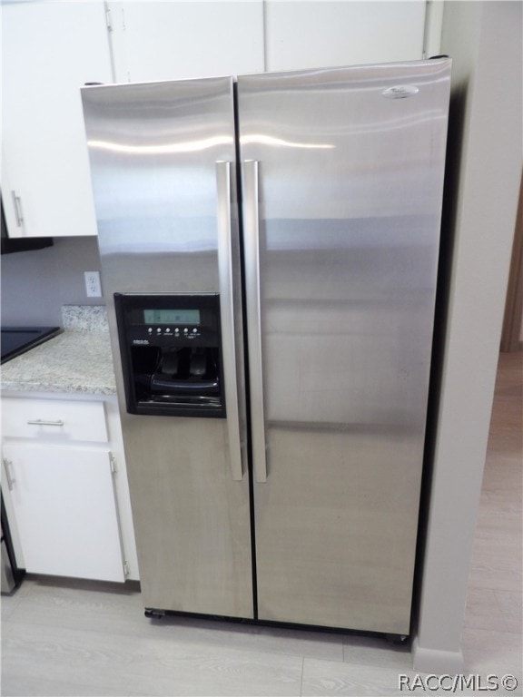 kitchen featuring white cabinets, stainless steel fridge, and light hardwood / wood-style floors