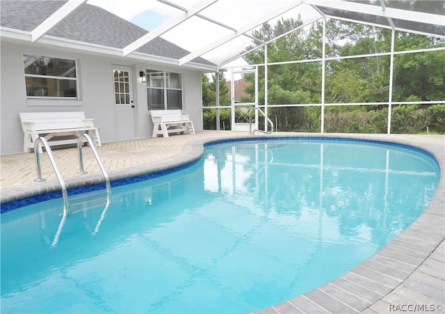 view of pool with glass enclosure and a patio area