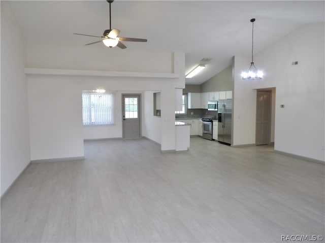 unfurnished living room featuring ceiling fan with notable chandelier, high vaulted ceiling, and light hardwood / wood-style flooring