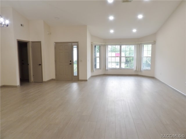 unfurnished living room featuring a chandelier and light hardwood / wood-style floors