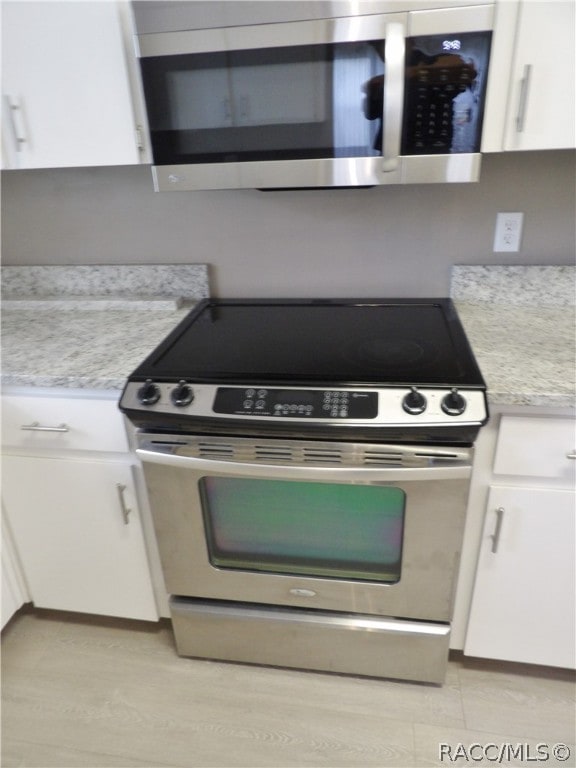 kitchen with light stone counters, white cabinets, and stainless steel appliances