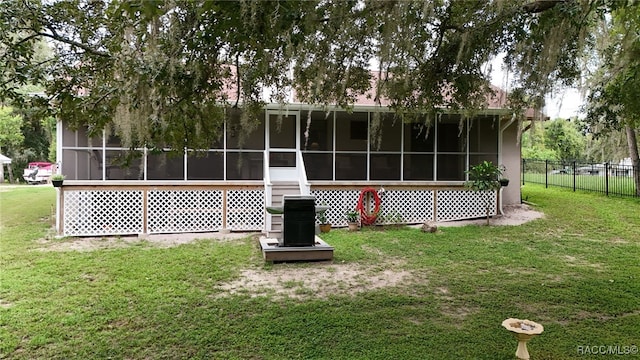 rear view of house featuring a lawn and a sunroom