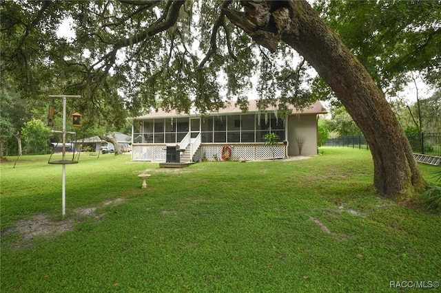 rear view of property featuring a lawn and a sunroom