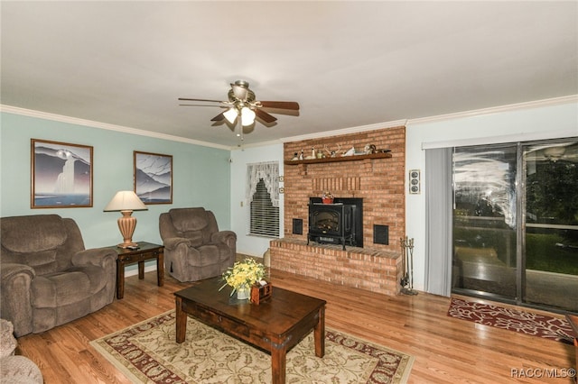 living room featuring hardwood / wood-style floors, a wood stove, ceiling fan, and ornamental molding