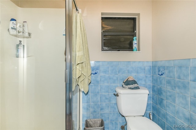 bathroom with a shower with door, tile walls, and toilet