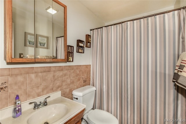 bathroom with walk in shower, vanity, tile walls, and toilet