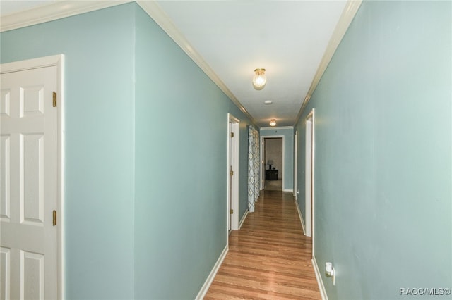 hall with light wood-type flooring and ornamental molding