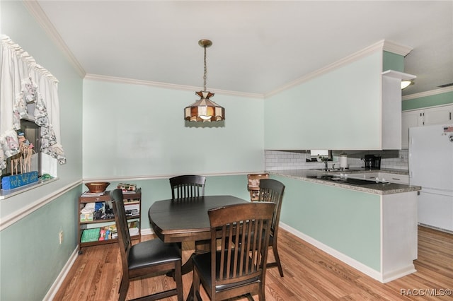 dining area with crown molding and light hardwood / wood-style flooring