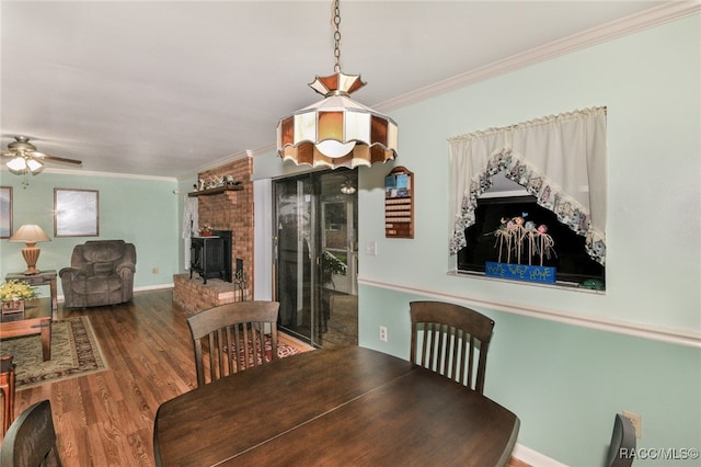 dining space featuring crown molding, a fireplace, ceiling fan, and hardwood / wood-style flooring