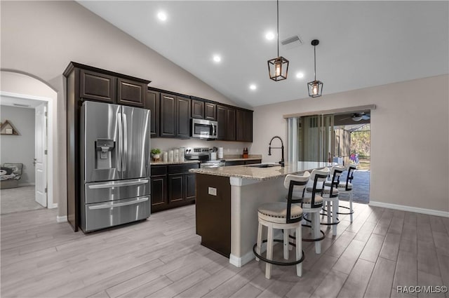 kitchen with sink, light stone counters, decorative light fixtures, a center island with sink, and stainless steel appliances