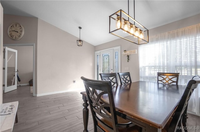 dining area featuring wood-type flooring and vaulted ceiling