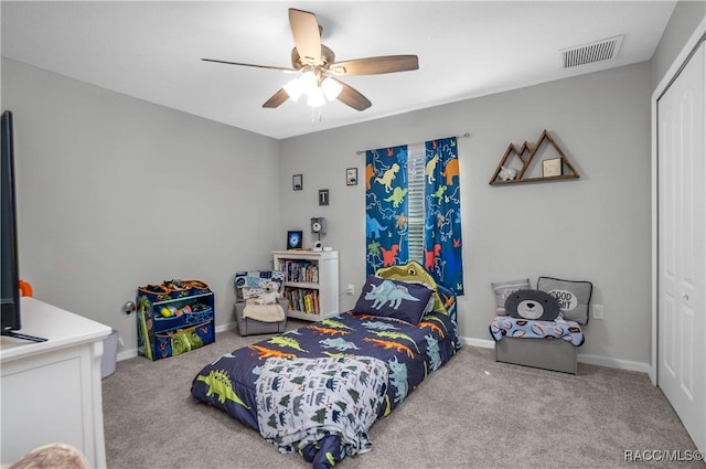 bedroom with ceiling fan, light carpet, and a closet