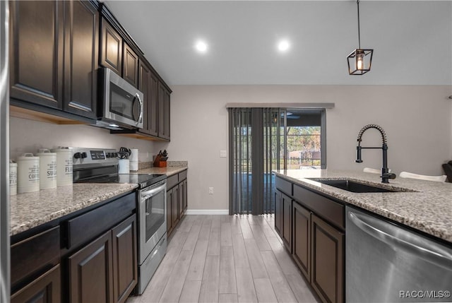 kitchen featuring sink, dark brown cabinets, stainless steel appliances, light stone counters, and light wood-type flooring